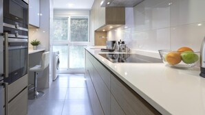 Una cocina moderna con un extractor de acero inoxidable, horno empotrado y un amplio ventanal que proporciona luz natural.