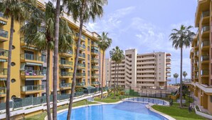 Un hotel con varios edificios amarillos, piscina y palmeras.