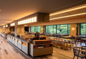 A modern restaurant with a long counter, multiple tables, and large windows offering a view of the outdoors. - Yamanaka Onsen KAJIKASO (Kaga)