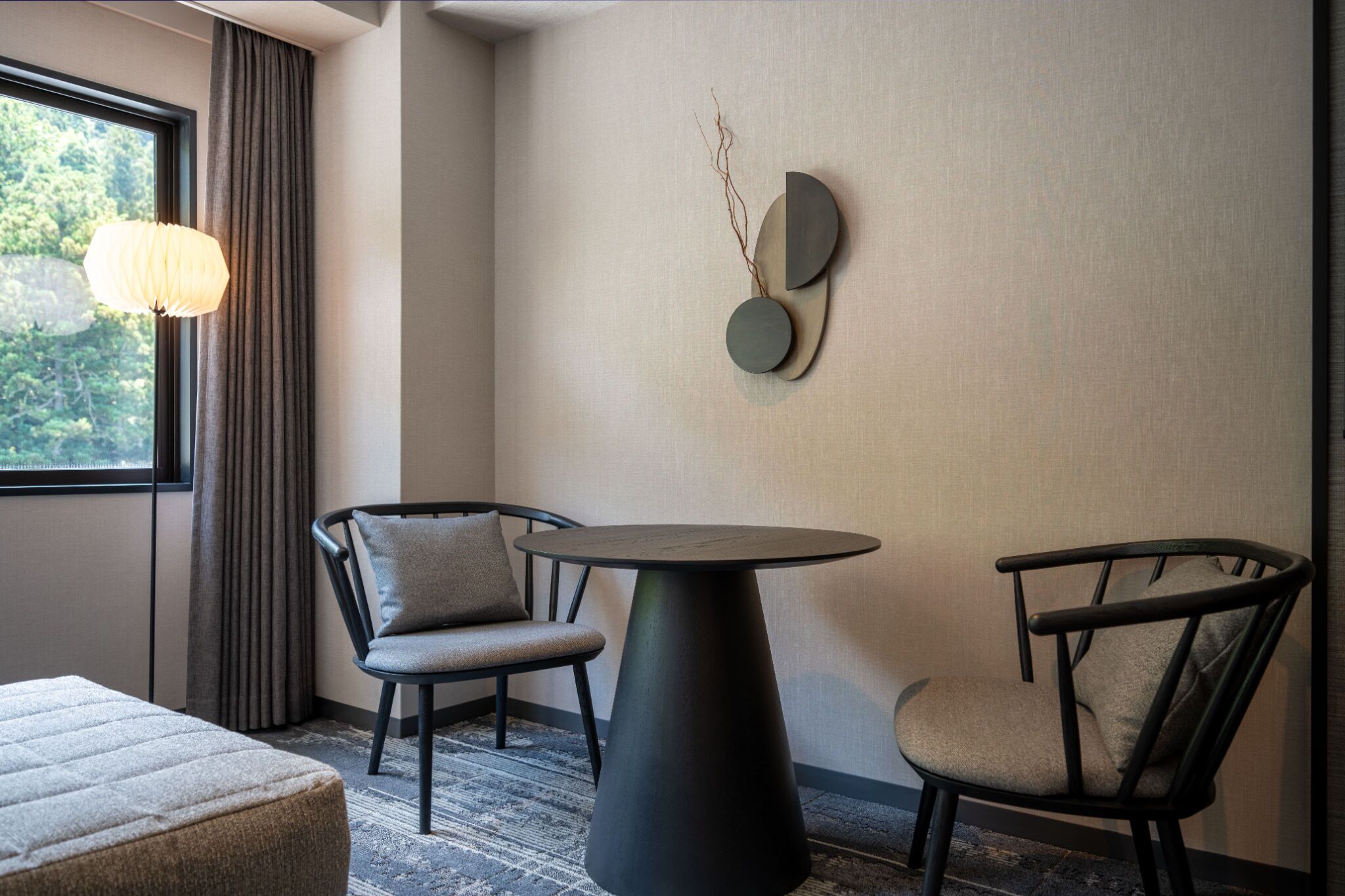 Une pièce moderne comprenant une table ronde, deux chaises, un canapé et un élément décoratif mural.