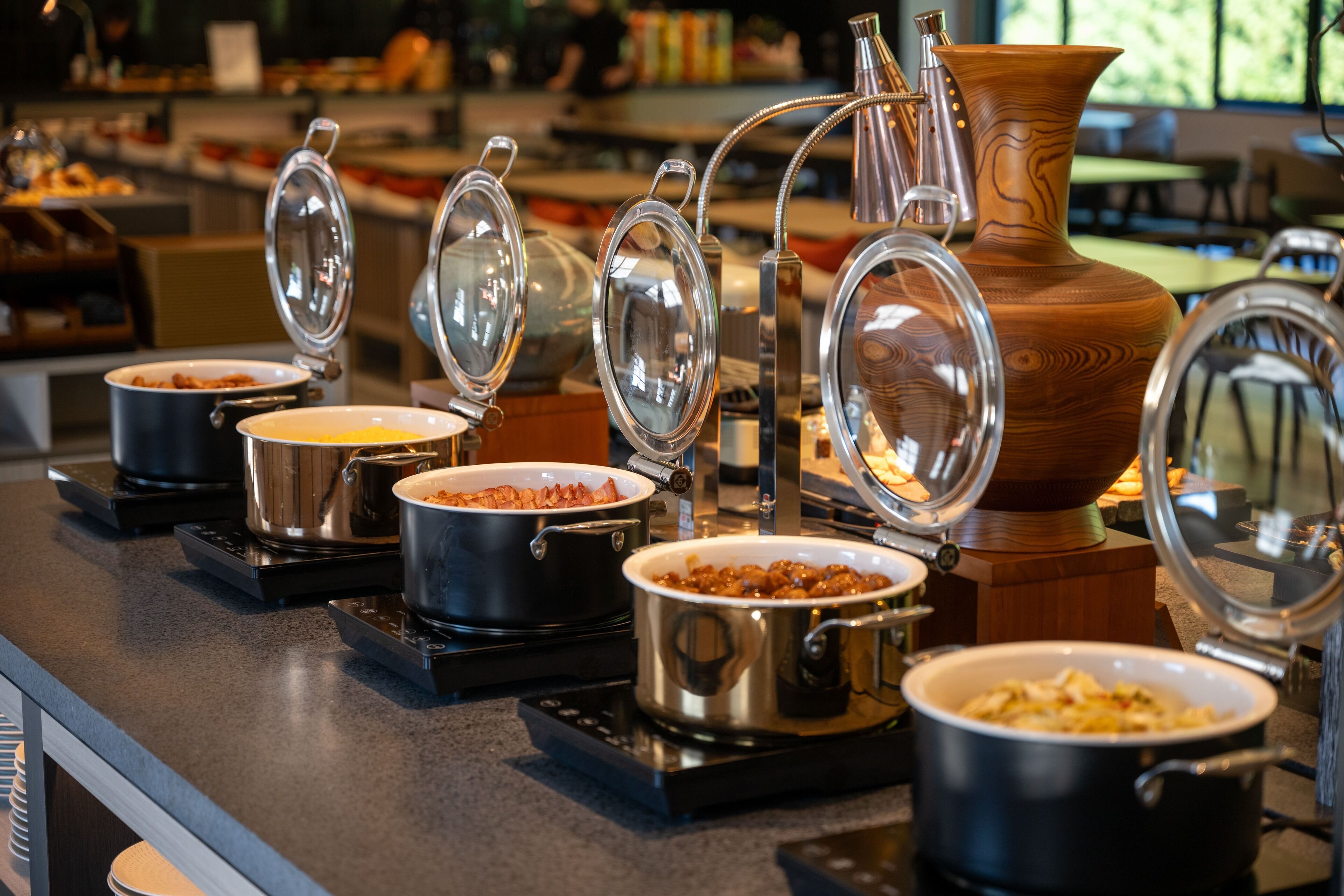 Montaje de bufé con diversos platos en ollas y recipientes, algunos con tapas.