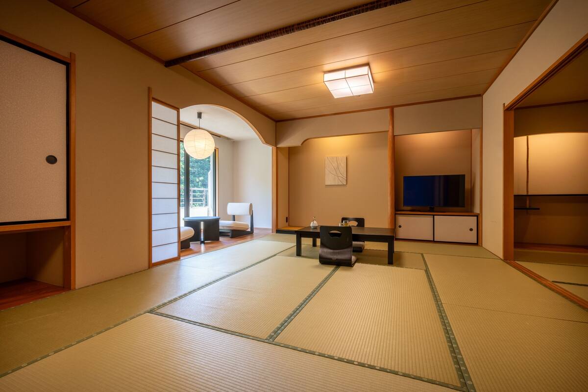 Um quarto japonês tradicional com tatames, uma mesa baixa e portas deslizantes.