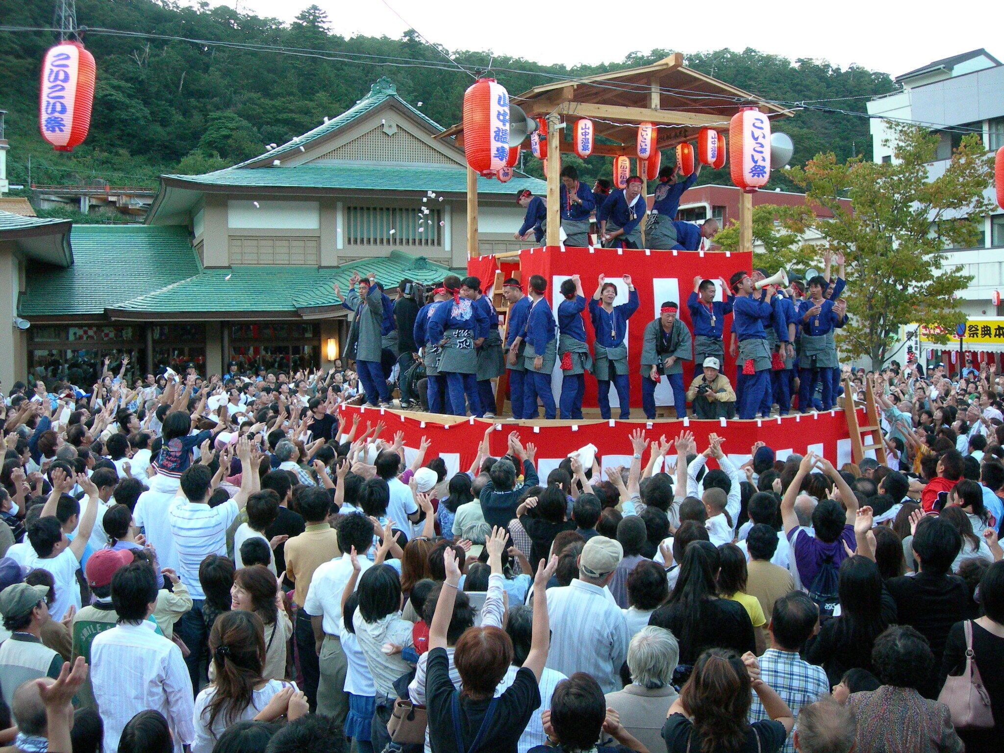 Een traditioneel Japans festival, met een menigte mensen rondom een podium.