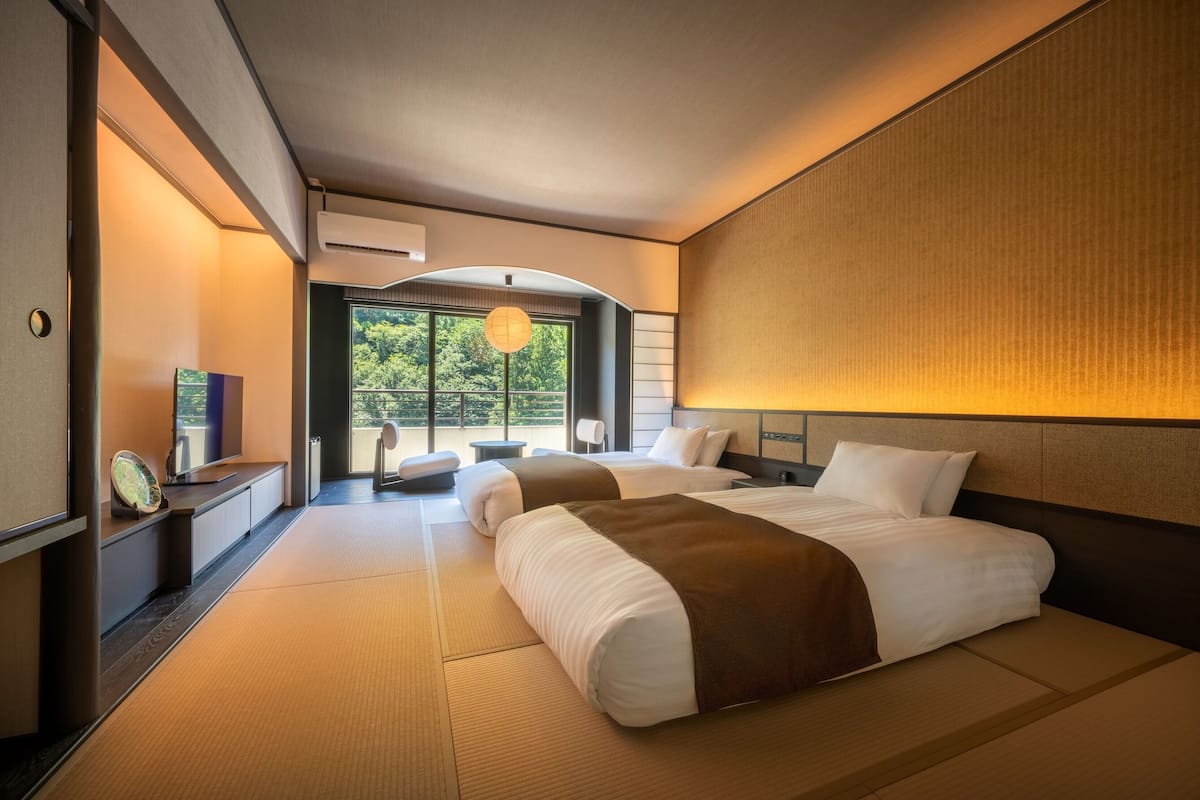 A hotel room with a large bed, a television, a desk, and a view of the outdoors.