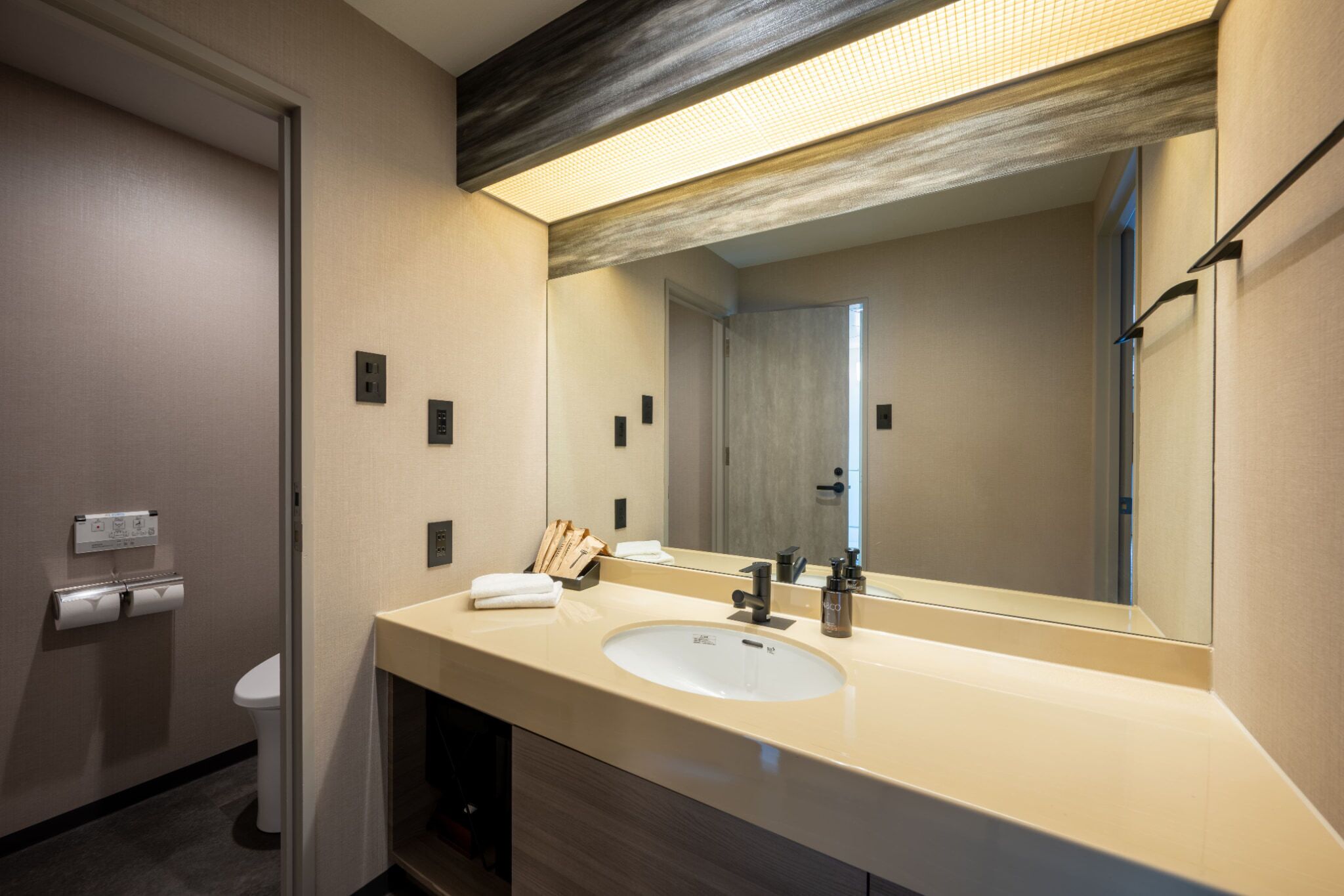 A modern bathroom with a large sink, mirror, and toilet.