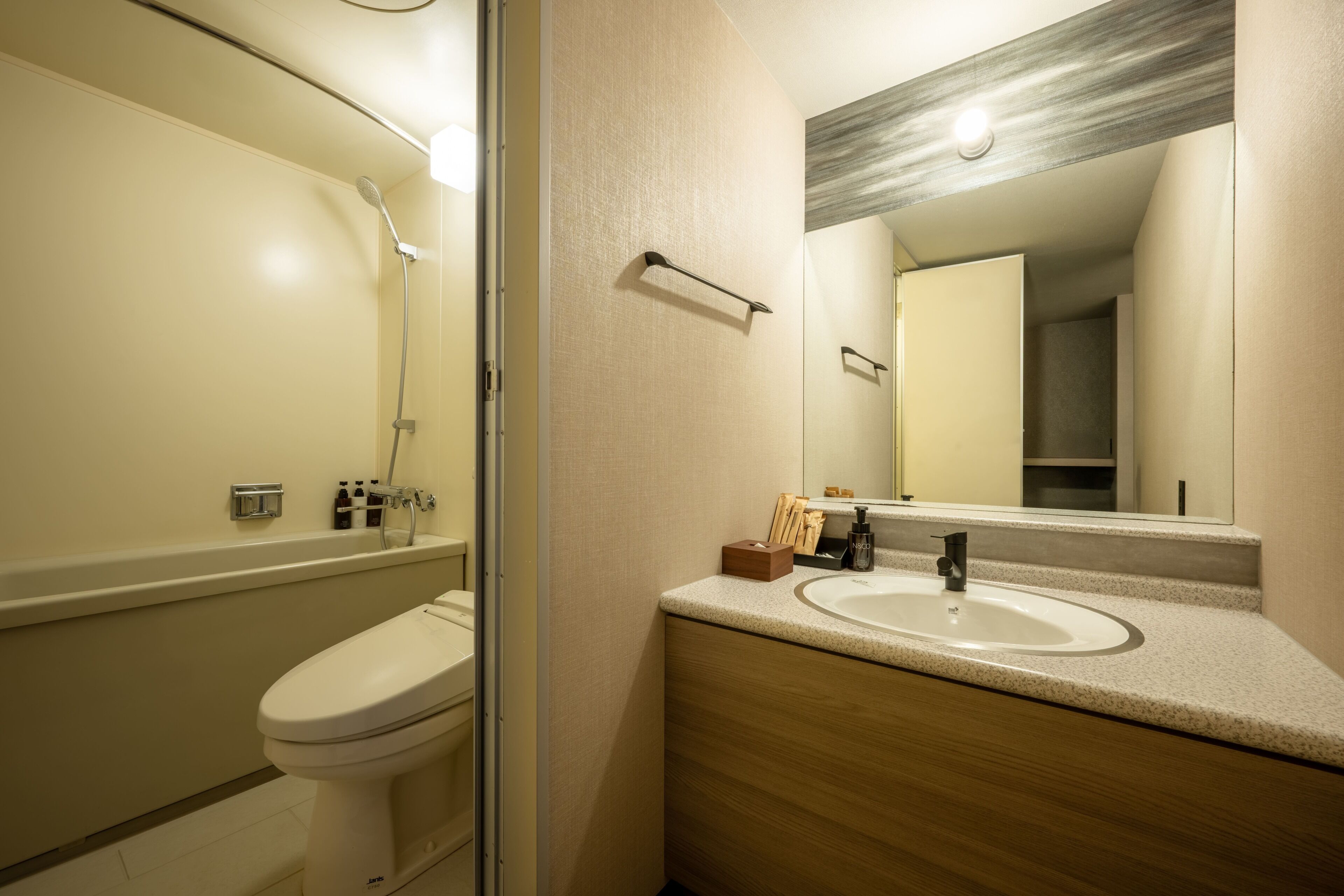 A modern bathroom with a toilet, a shower, a sink, and a mirror.