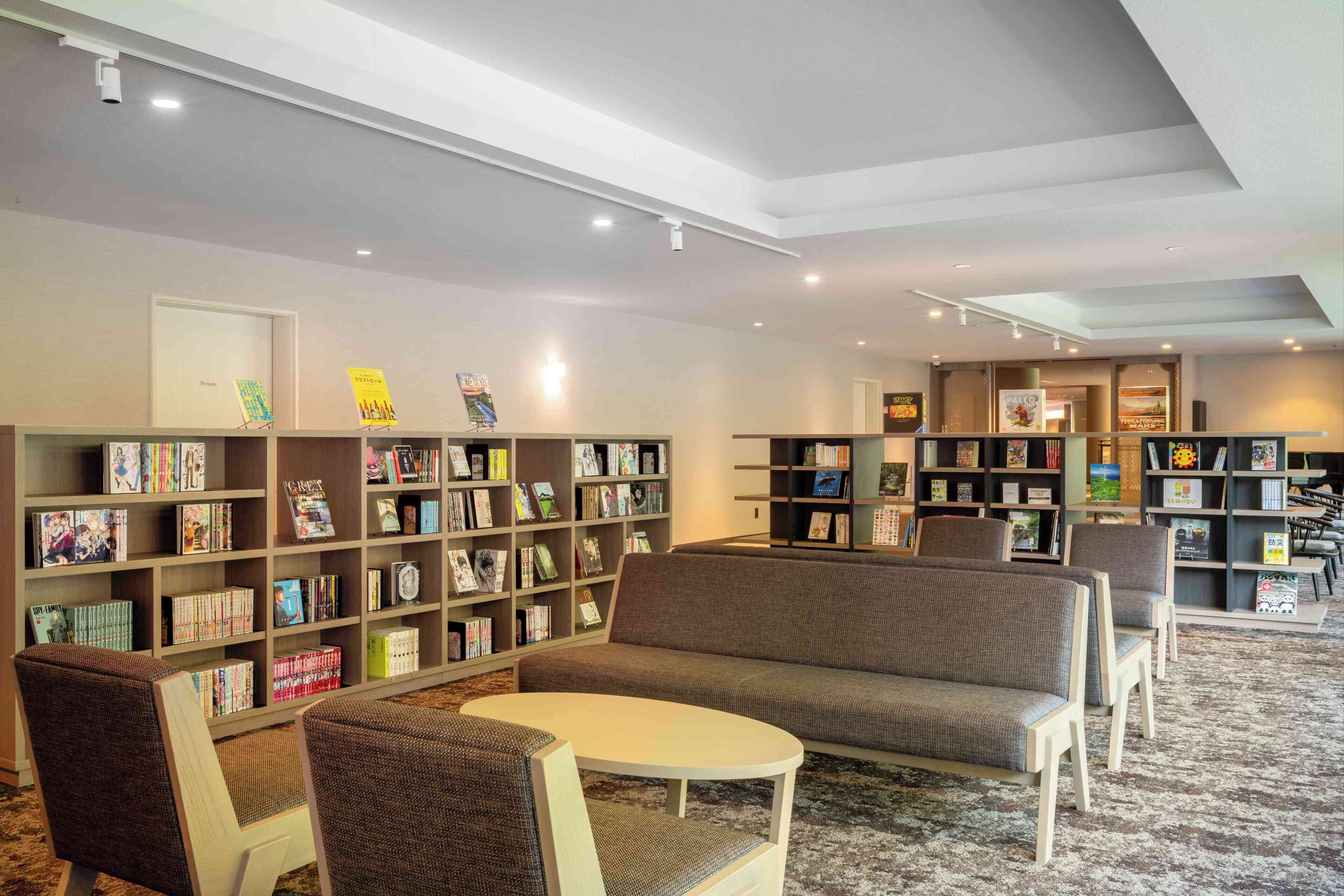 Uma biblioteca com diversas áreas de estar, estantes de livros e um teto com iluminação embutida.
