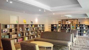 Uma biblioteca com diversas áreas de estar, estantes de livros e um teto com iluminação embutida.