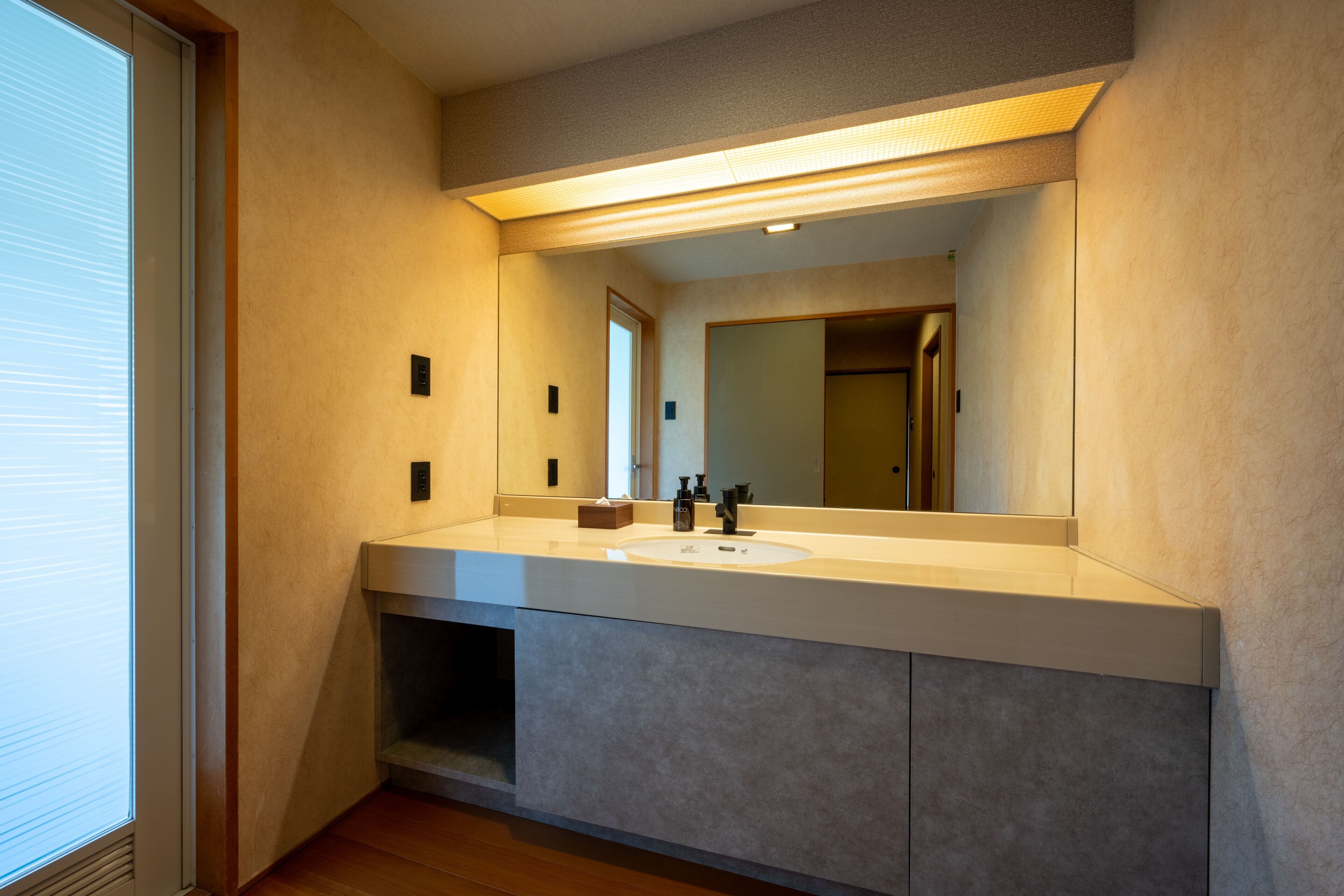 Un baño moderno con un espejo grande, un lavamanos y un mueble de tocador.
