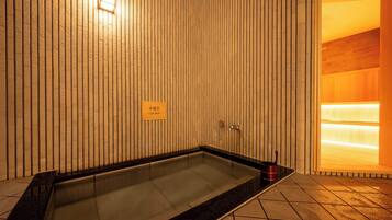 Area benessere con parete in legno, cartello che indica una vasca fredda e pavimento piastrellato.