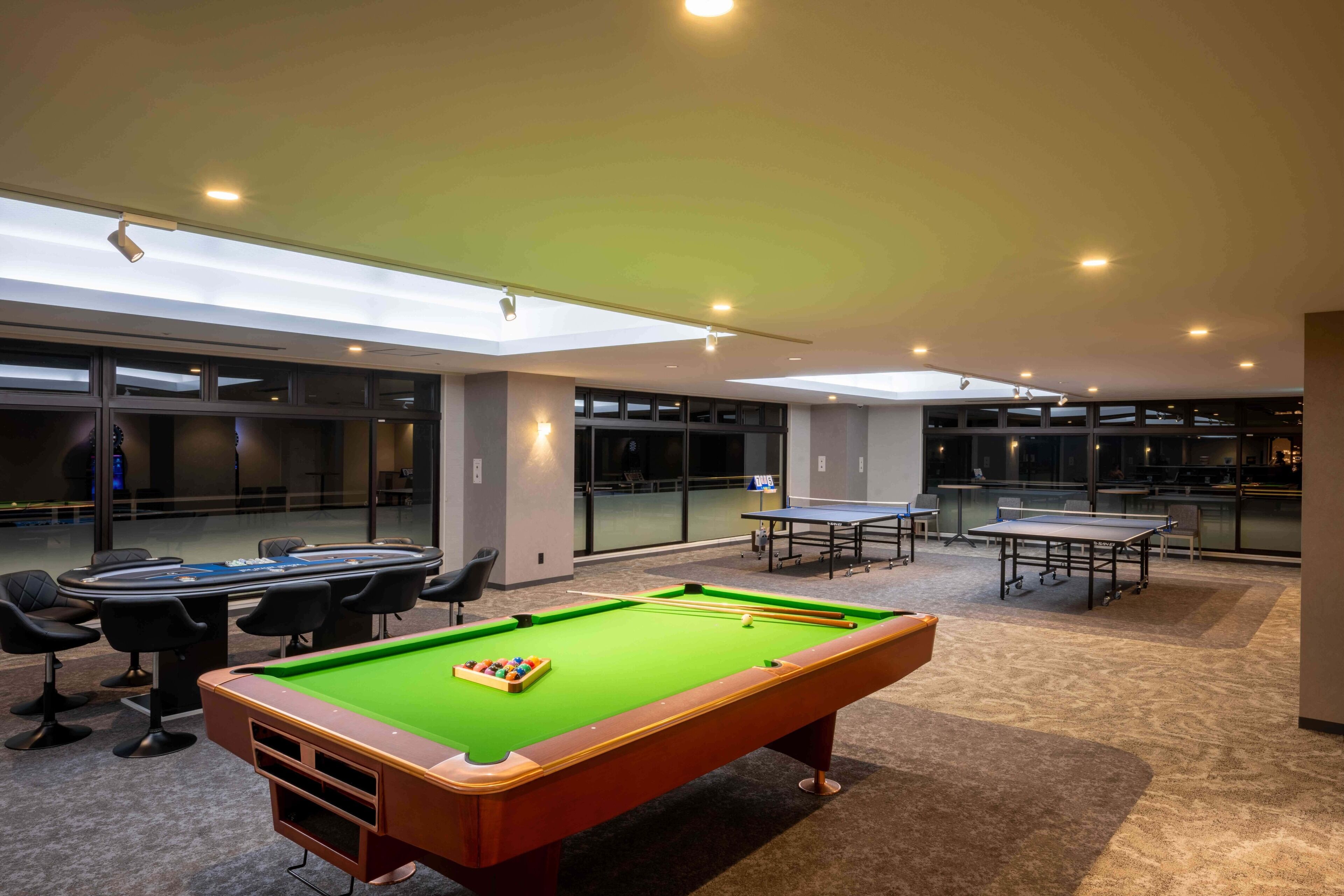 A pool table with a green felt surface, a billiards table, and a seating area with chairs.