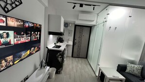 Un espace de vie compact comprenant un coin cuisine, un petit coin repas et un espace détente avec un canapé et une table.
