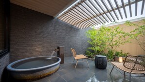 Un espace de détente extérieur moderne, doté d’un jacuzzi, de sièges et d’une pergola offrant de l’ombre.