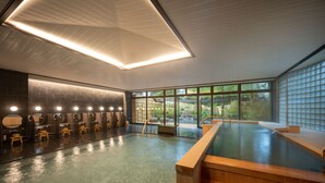 Een modern binnenzwembad met een houten bankje, een sauna en een rij kleedkamers.