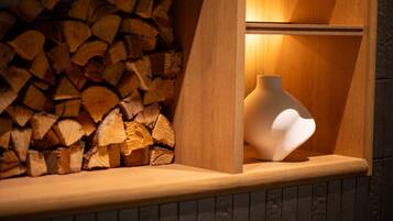 A wooden shelf with a white vase and a stack of firewood.
