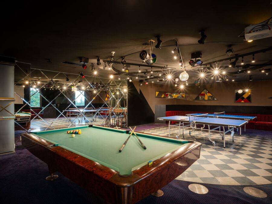 Una mesa de billar con piso a cuadros, una mesa de pool y un proyector montado en el techo.