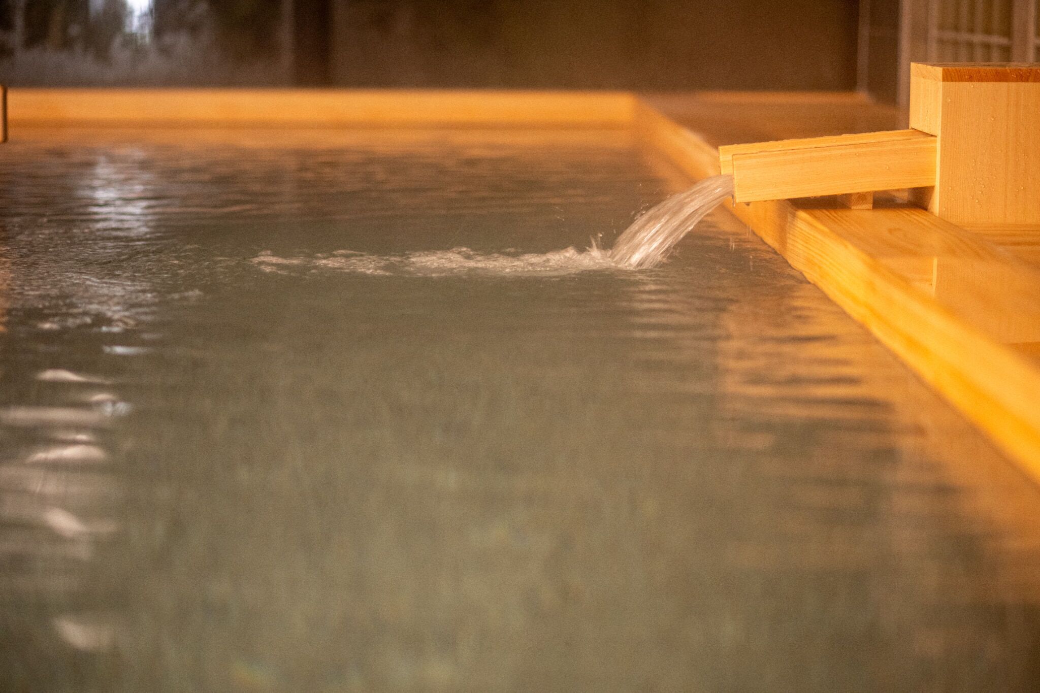 A wooden bench by a water feature in a public space.