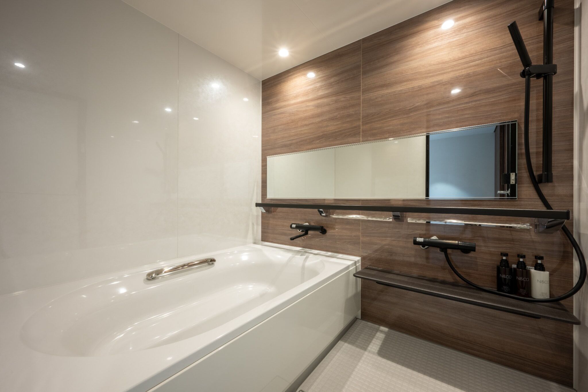 A modern bathroom with a large bathtub, a wooden vanity with a mirror, and a shower area.