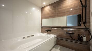 A modern bathroom with a large bathtub, a wooden vanity with a mirror, and a shower area.