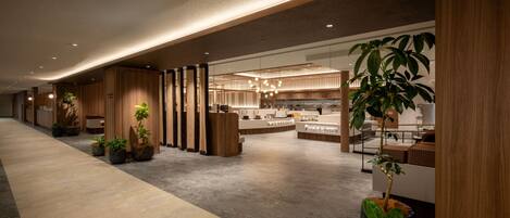 Un moderno vestíbulo de hotel con paneles de madera, una recepción y plantas en macetas.
