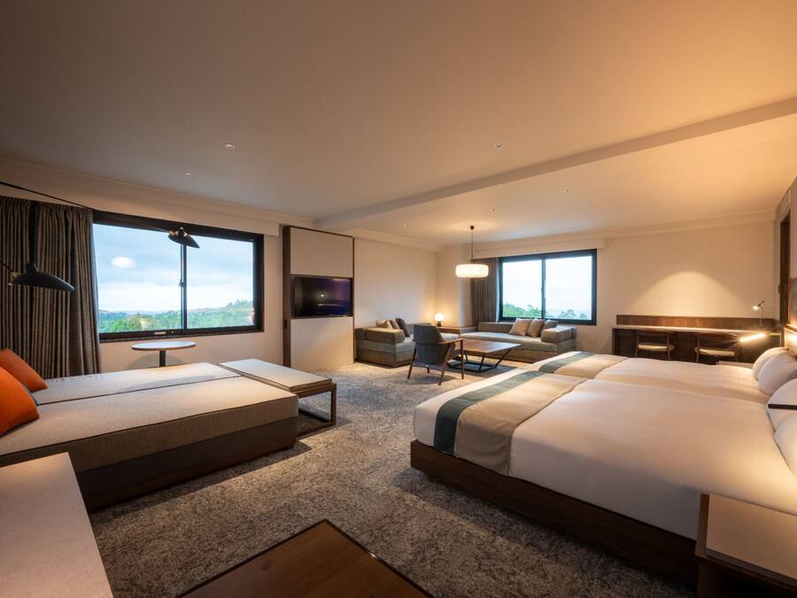 Une chambre d’hôtel moderne, dotée d’un grand lit, d’un canapé, d’un bureau et offrant une vue sur l’extérieur.