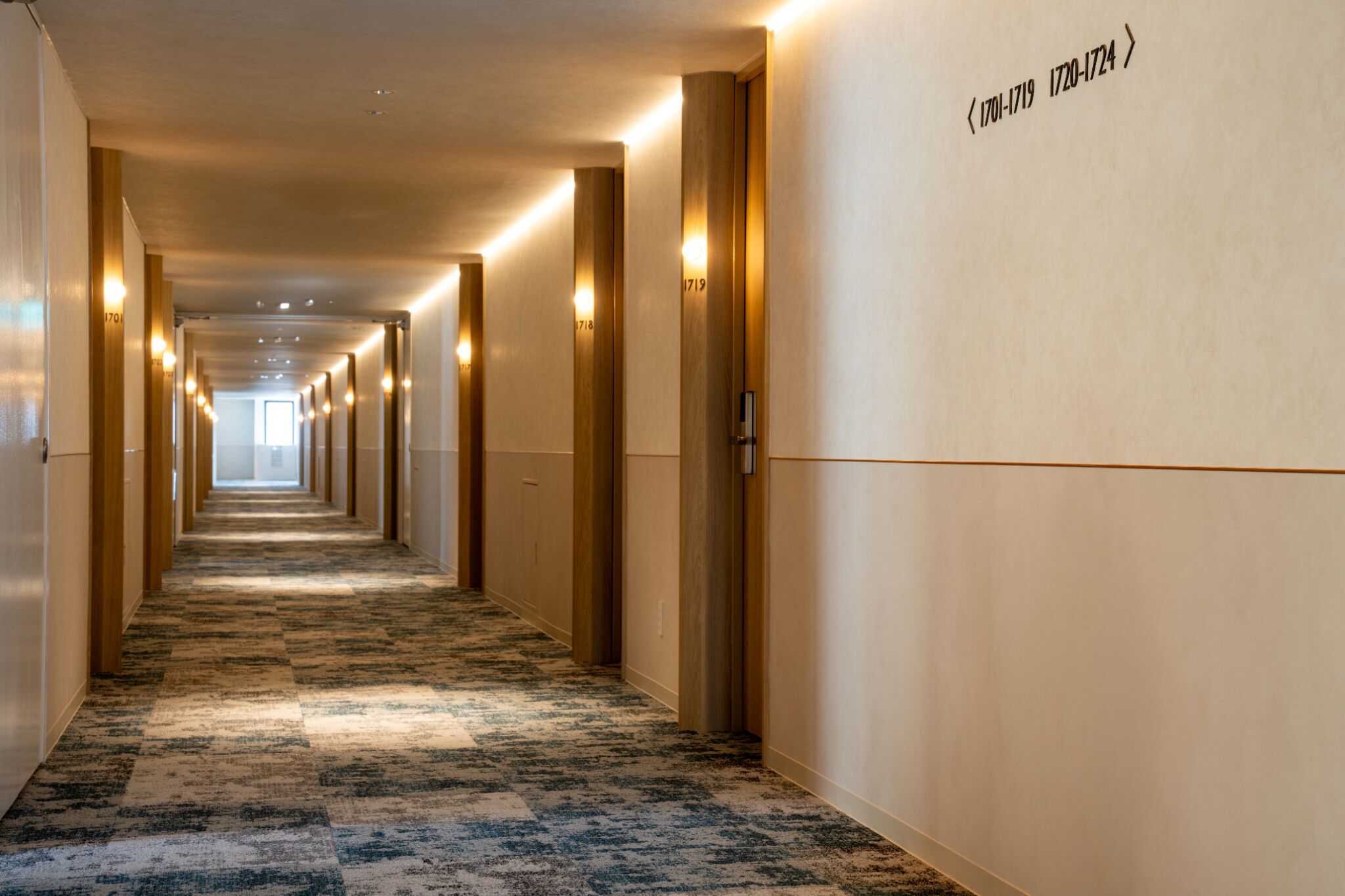 Un couloir d'hôtel avec des revêtements de sol en moquette, des lambris en bois et des appliques murales.