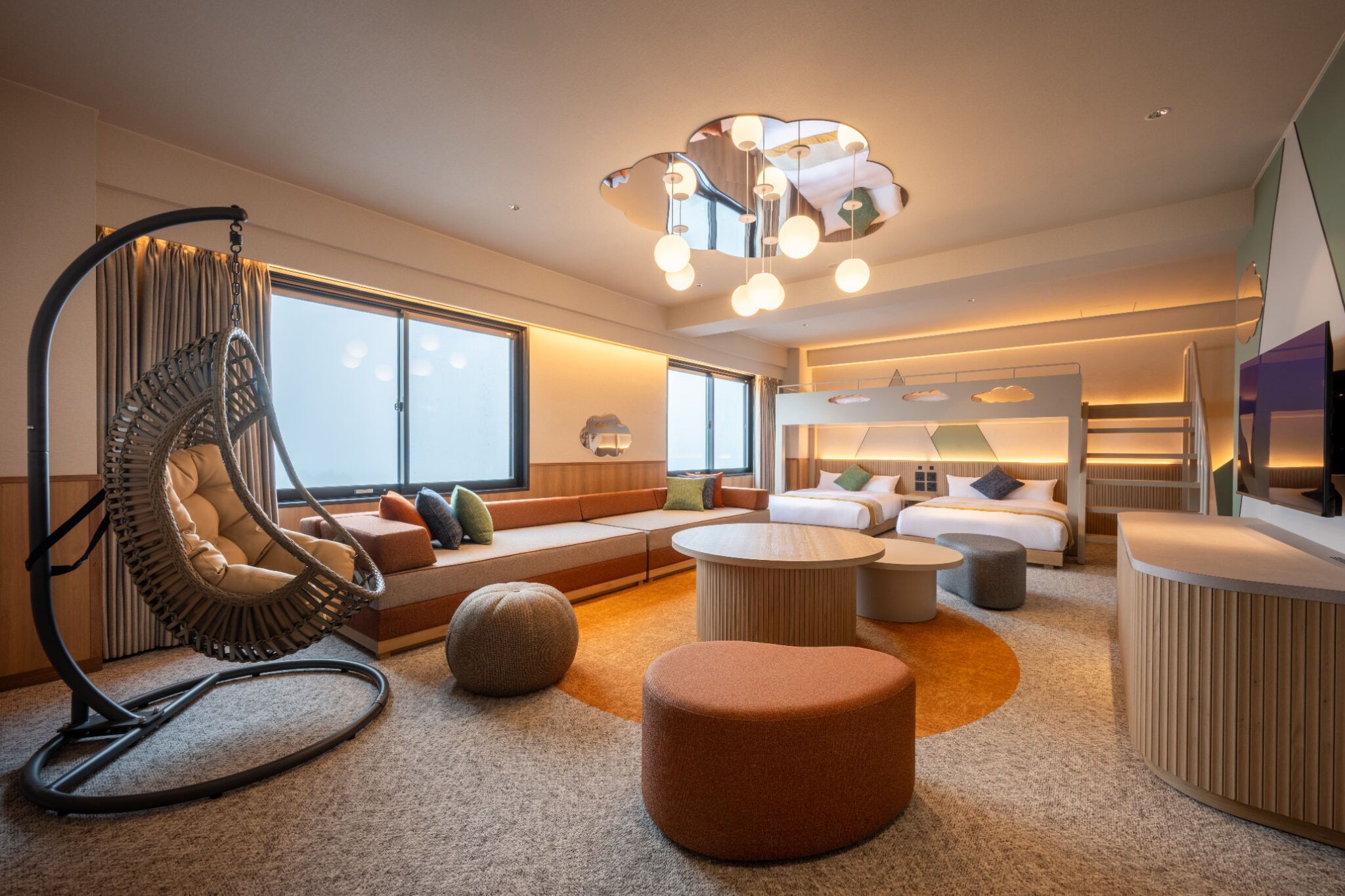 A modern hotel room with a large window, a hanging chair, a sofa, a round coffee table, and a bed with a headboard.