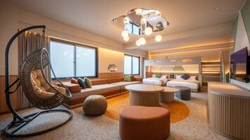A modern hotel room with a large window, a hanging chair, a sofa, a round coffee table, and a bed with a headboard.
