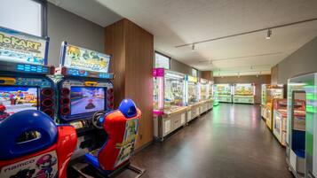 Una hilera de juegos de arcade en un espacio interior bien iluminado, con paneles de madera y ventanas grandes.