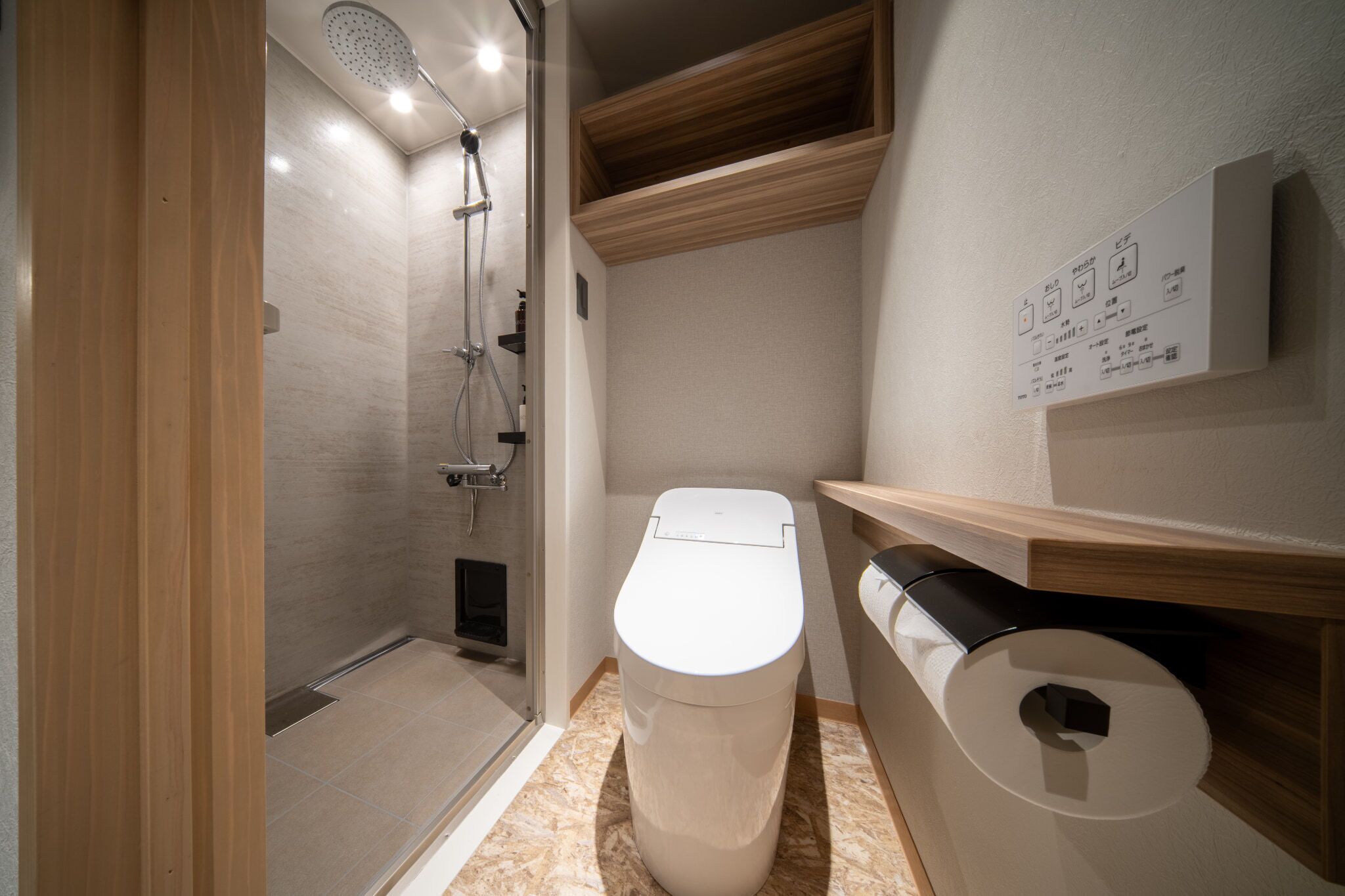 A modern bathroom with a shower, toilet, and a wooden shelf.