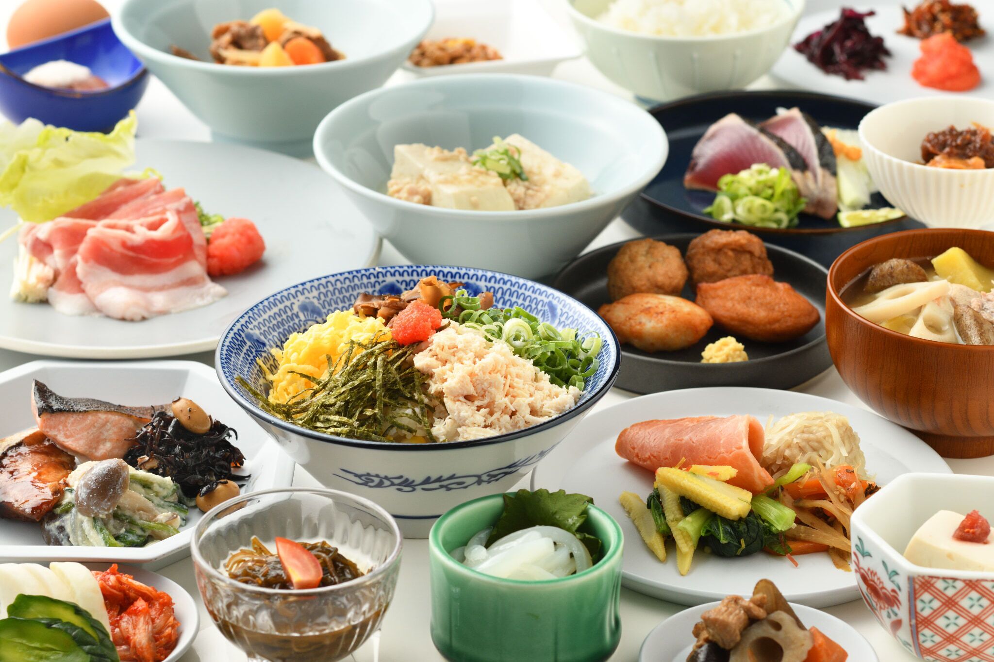 A variety of dishes on a table, including sushi, sashimi, and other Asian cuisine.