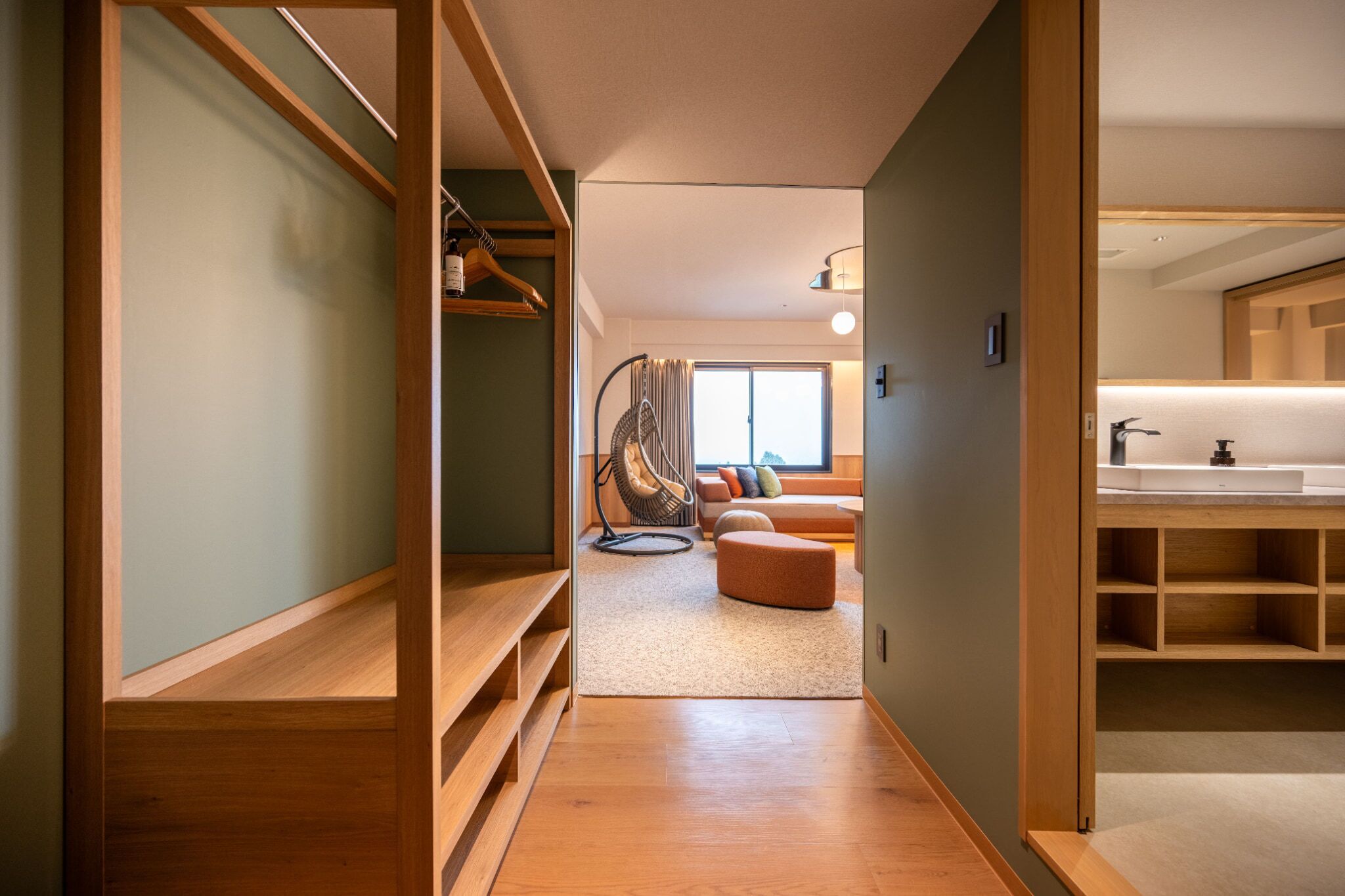 A modern interior with a wooden staircase, a seating area with cushions, and a kitchen with a sink.