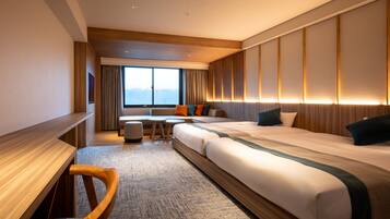 A hotel room with a large bed, a desk, a chair, a small table, and a view of the mountains through the window.