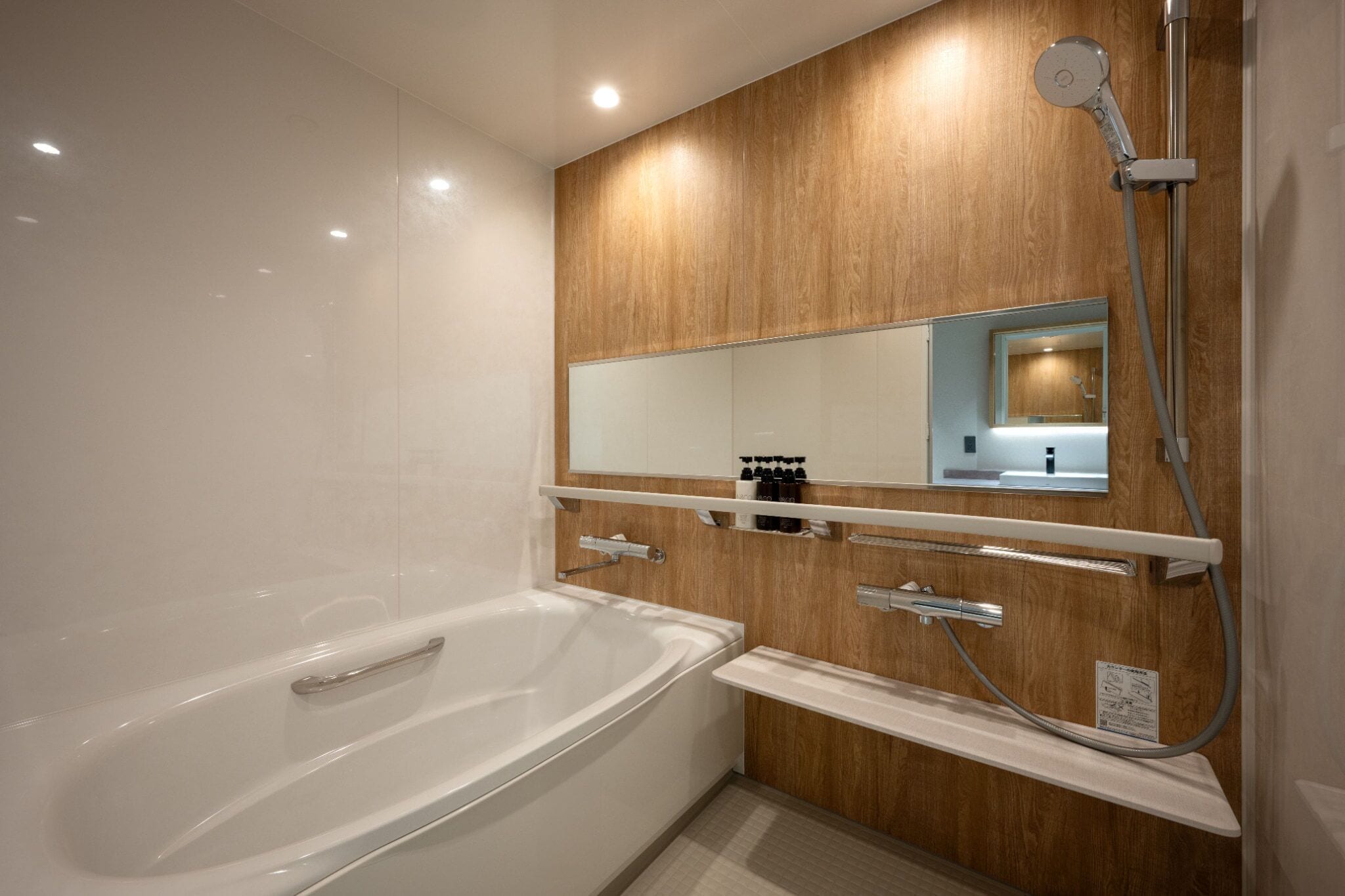 A modern bathroom with a large bathtub, a shower, and a wooden wall panel.