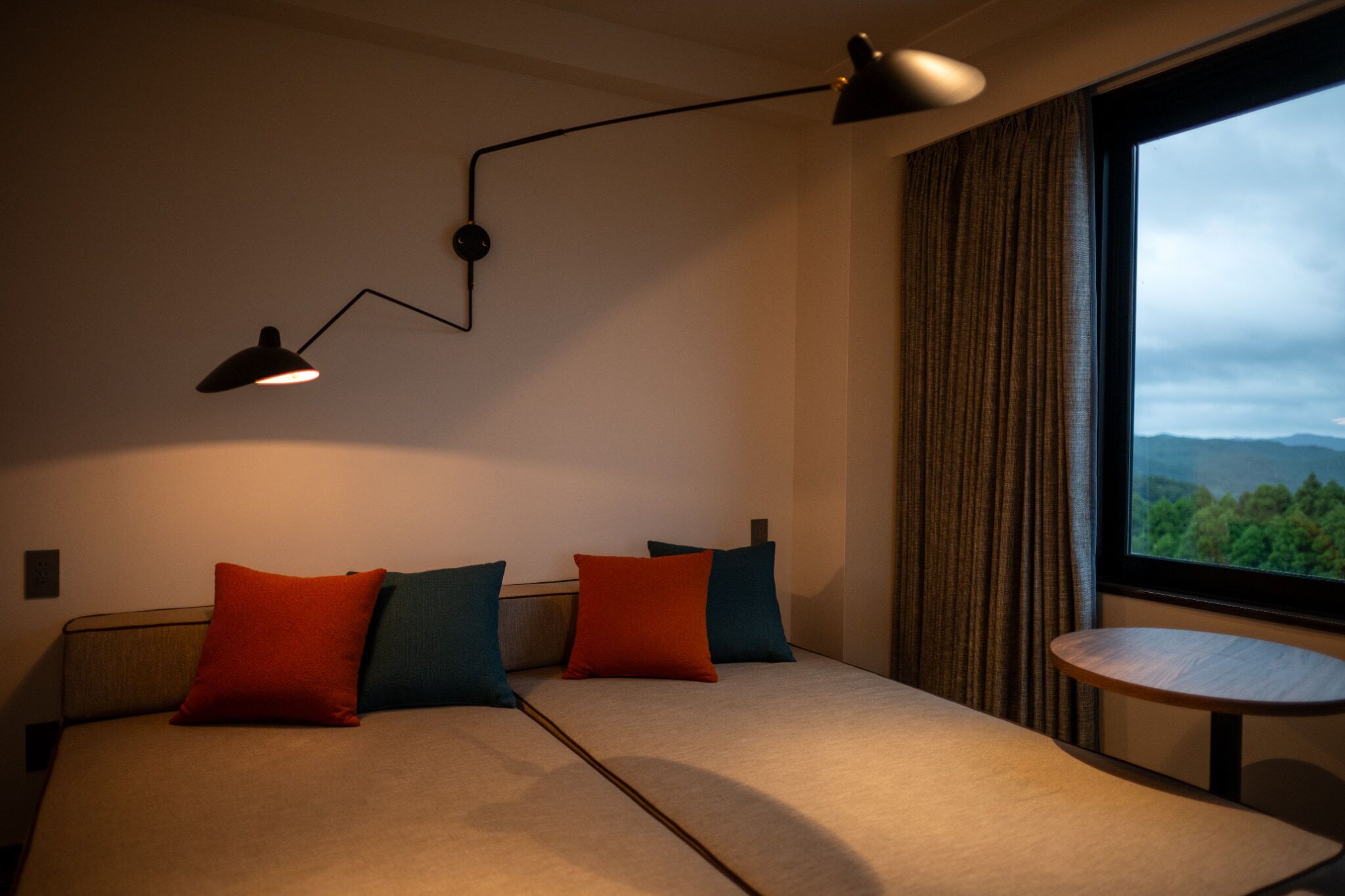 Ein Hotelzimmer mit einem Bett, einem kleinen Tisch und einem Fenster mit Blick ins Freie.