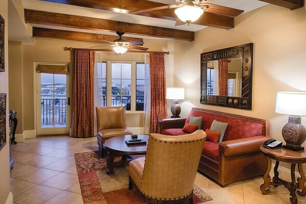 A living room with a leather sofa, a round coffee table, and a ceiling fan.
