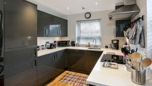 A modern kitchen with dark cabinets, a microwave, a coffee maker, and a window with blinds.