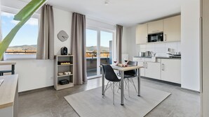 A modern kitchen with a dining area, a clock, and a view of the outdoors.