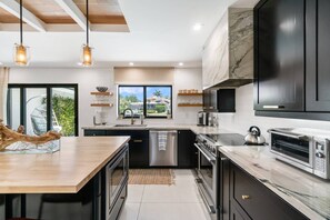 A modern kitchen with a central island, stainless steel appliances, and a view of a residential area.