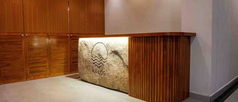 A reception area with a stone counter, wooden paneling, and a tiled floor.