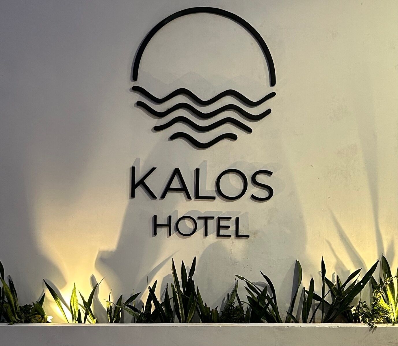A sign for the Kalos Hotel with a wave design above the name.