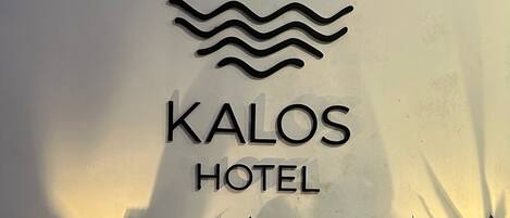 A sign for the Kalos Hotel with a wave design above the name.