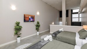 Een moderne hotelkamer met twee bedden, een flatscreen televisie aan de muur en twee potplanten.