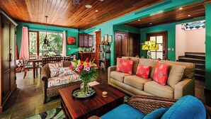 A spacious living room with a wooden ceiling, a beige sofa with red pillows, a dining area with a table and chairs, and a bookshelf. - Villa del BroDor Amor, beautiful home with access to 2 beaches Tamarindo and Langosta (Playa Langosta)