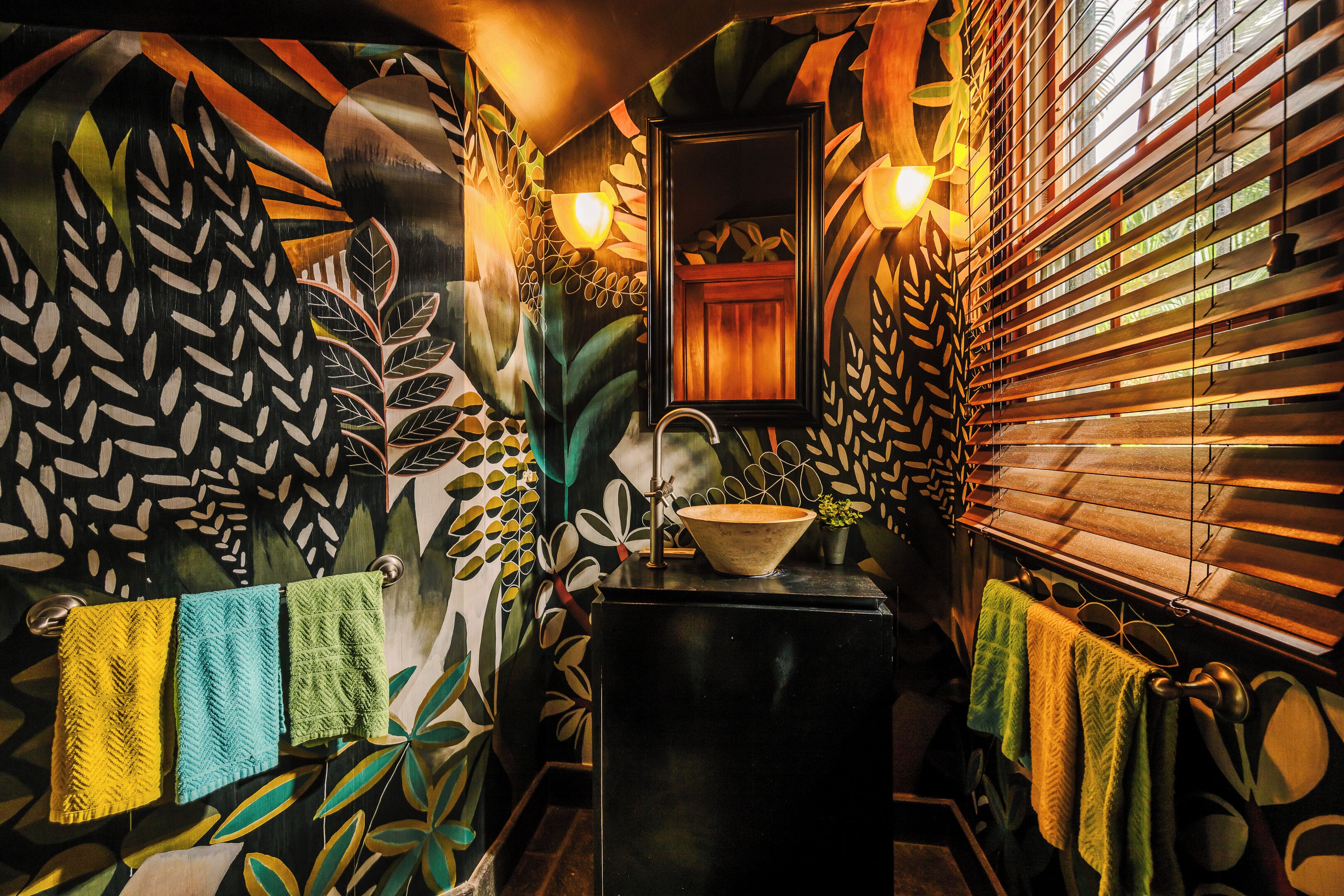 A bathroom with a black sink, wooden blinds, and a mirror.