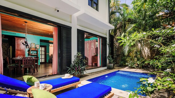A poolside area with lounge chairs, a small table, and a potted plant. - Villa del BroDor Amor, beautiful home with access to 2 beaches Tamarindo and Langosta (Playa Langosta)