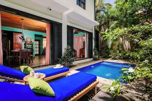 Un espace aménagé au bord de la piscine, avec des chaises longues, une petite table et une plante en pot.
