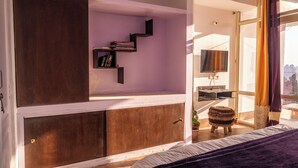 A bedroom with a bed, a bookshelf, a television, and a window with curtains.