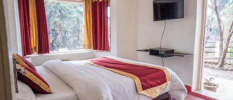 A hotel room with a bed, a TV mounted on the wall, and a window with curtains.