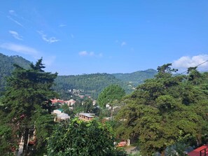 A mountainous landscape with buildings and trees. - Dew Drops Homestay (Nainital)